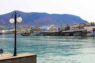 Sea by mountains against clear sky