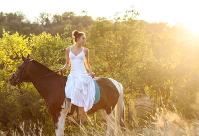 Woman riding horse on field