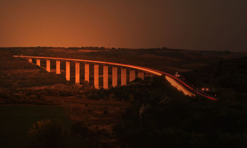 Bridge over road against sky at night