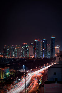 Illuminated city by buildings against sky at night