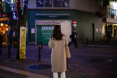 Rear view of woman standing at night