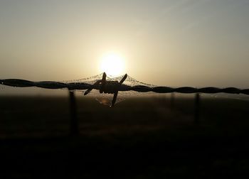 Close-up of barbed wire against sky during sunset