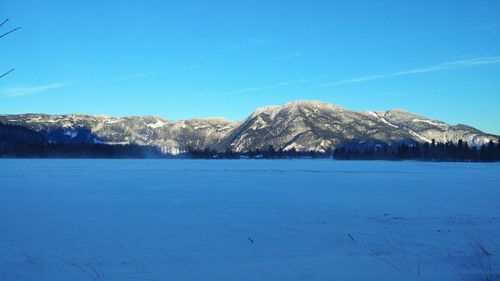 Scenic view of frozen lake against blue sky