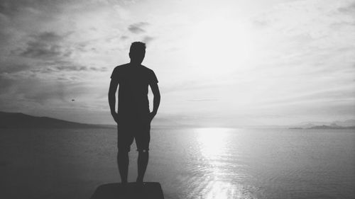 Rear view of a silhouette man overlooking calm sea