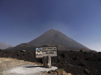 Information sign on mountain against clear blue sky