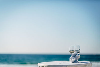 View of drink on table at sea against clear sky