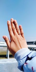 Cropped hand of woman with ring against clear sky