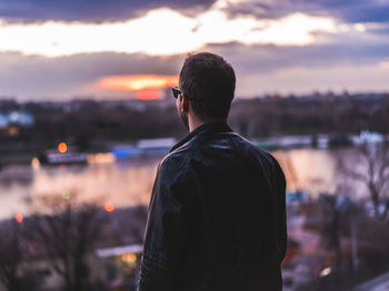 Rear view of man standing against cloudy sky