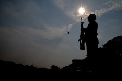 Low angle view silhouette army soldier standing against sky during sunset