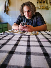 Young man using mobile phone while sitting on table at home