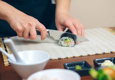 Midsection of person holding sushi on table
