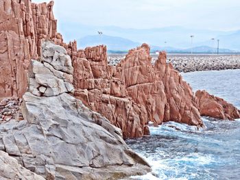 Rock formation by sea against sky