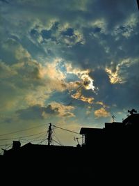 Low angle view of silhouette buildings against cloudy sky