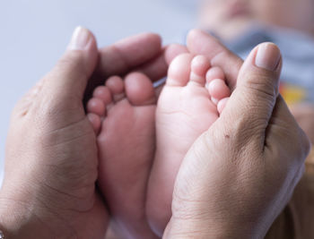 Cropped hands of parent holding baby barefoot