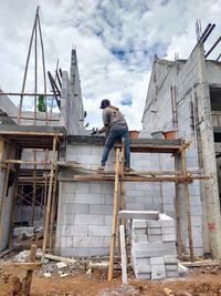 Low angle view of crane at construction site against sky