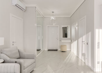 Bright entrance hall in a modern monotonous interior with a large mirrored wardrobe and sun rays