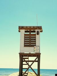 Lifeguard hut on beach against clear blue sky