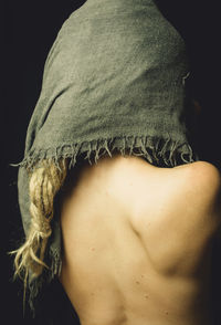 Rear view of seductive woman with scarf on head against black background