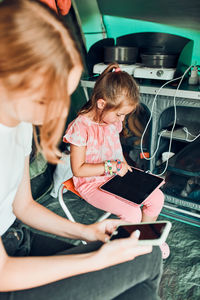 Sisters spending family time in a tent on camping. children using tablet playing games online