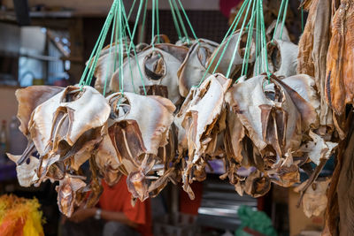 Dried fish tied into several bundles for sale, hanging from above, in a local market.
