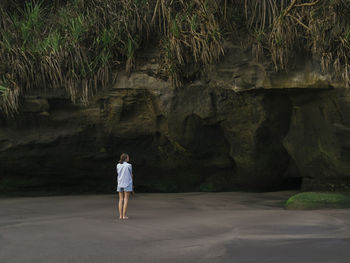 Young woman looking at cave at the beach