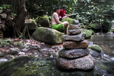 Stack of stones in stream with people fishing in background