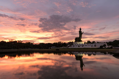 Reflection of statue in lake during sunset