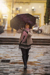 Full length of woman with umbrella standing in rain