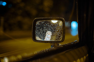 Raindrops on side-view mirror of car at night