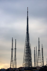 Low angle view of communications tower against cloudy sky