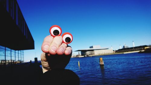 Close-up of hands against blue sky