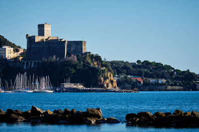 Sea by buildings against clear sky