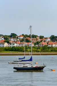 Boats in sea against clear blue sky