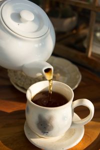 Close-up of tea being poured in cup on table