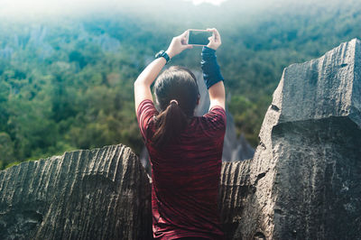 Rear view of woman using mobile phone on tree