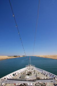 Sailboat sailing in sea against clear blue sky