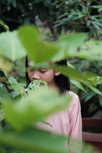 Portrait of girl standing by plant on field