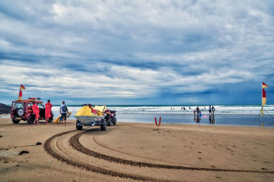 Trailer moving on beach against cloudy sky