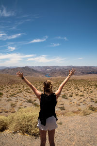 Rear view of man standing on land against sky