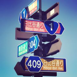 Low angle view of road sign against clear blue sky