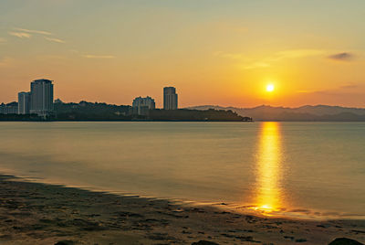 Scenic view of sea and buildings against sky during sunset