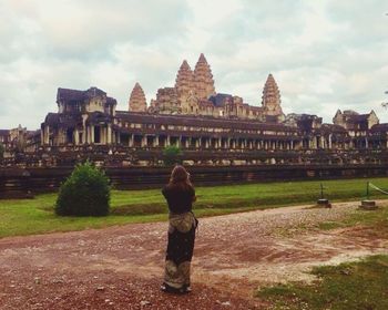 Rear view of a woman standing in front of historical building