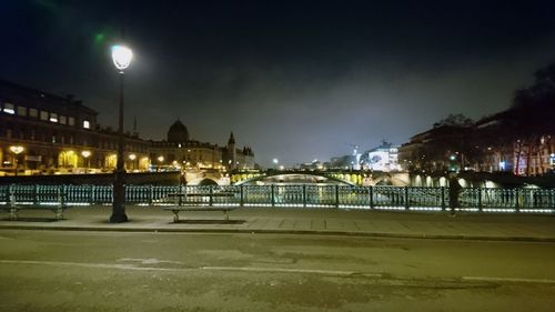 Illuminated city by sea against sky at night