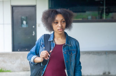 Portrait of beautiful young woman standing against wall