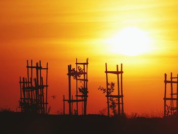 Silhouette cranes against sky during sunset