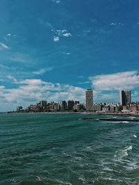 Sea by buildings against blue sky