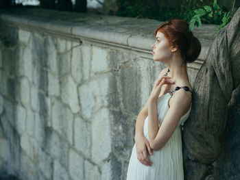 Side view of woman standing against wall