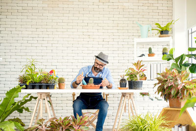 Portrait of smiling senior man using laptop while standing against wall