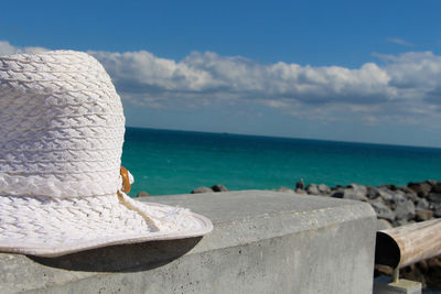 Close-up of white sun hat on retaining wall against sky