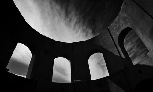 Low angle view of coit tower arches against cloudy sky
